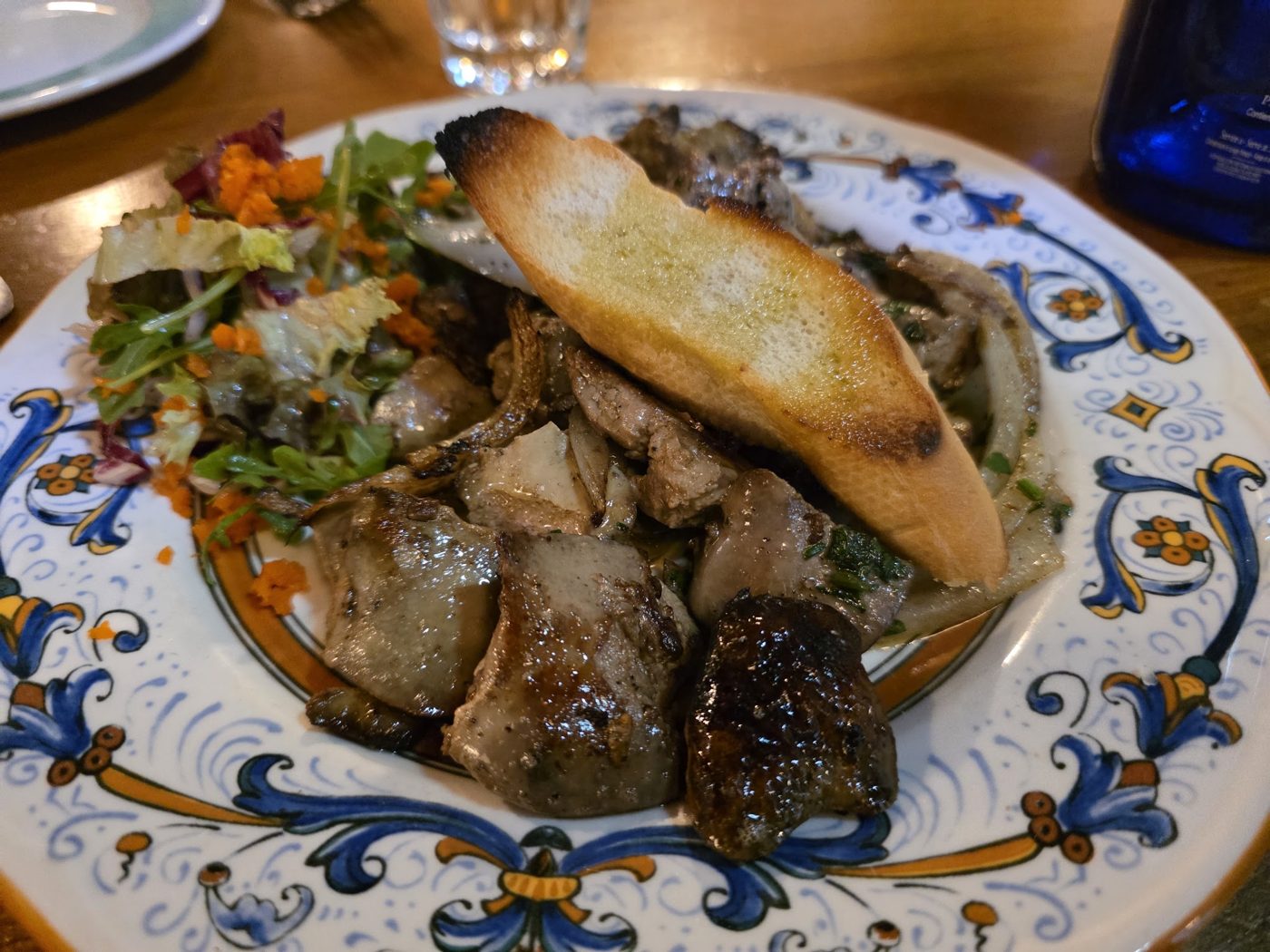 Grilled mushrooms and vegetables with toasted bread on a painted plate