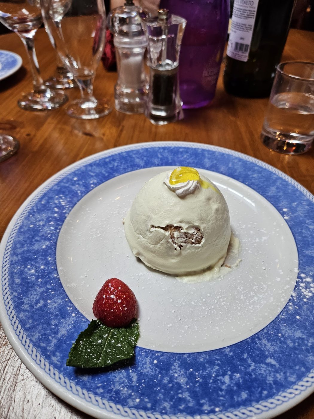 A white dessert with a strawberry on a blue plate