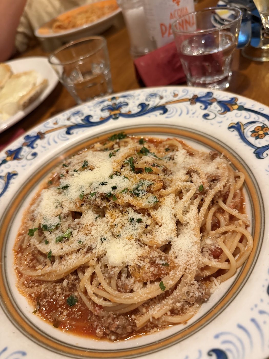 Spaghetti with ragù and grated cheese on a blue-rimmed plate